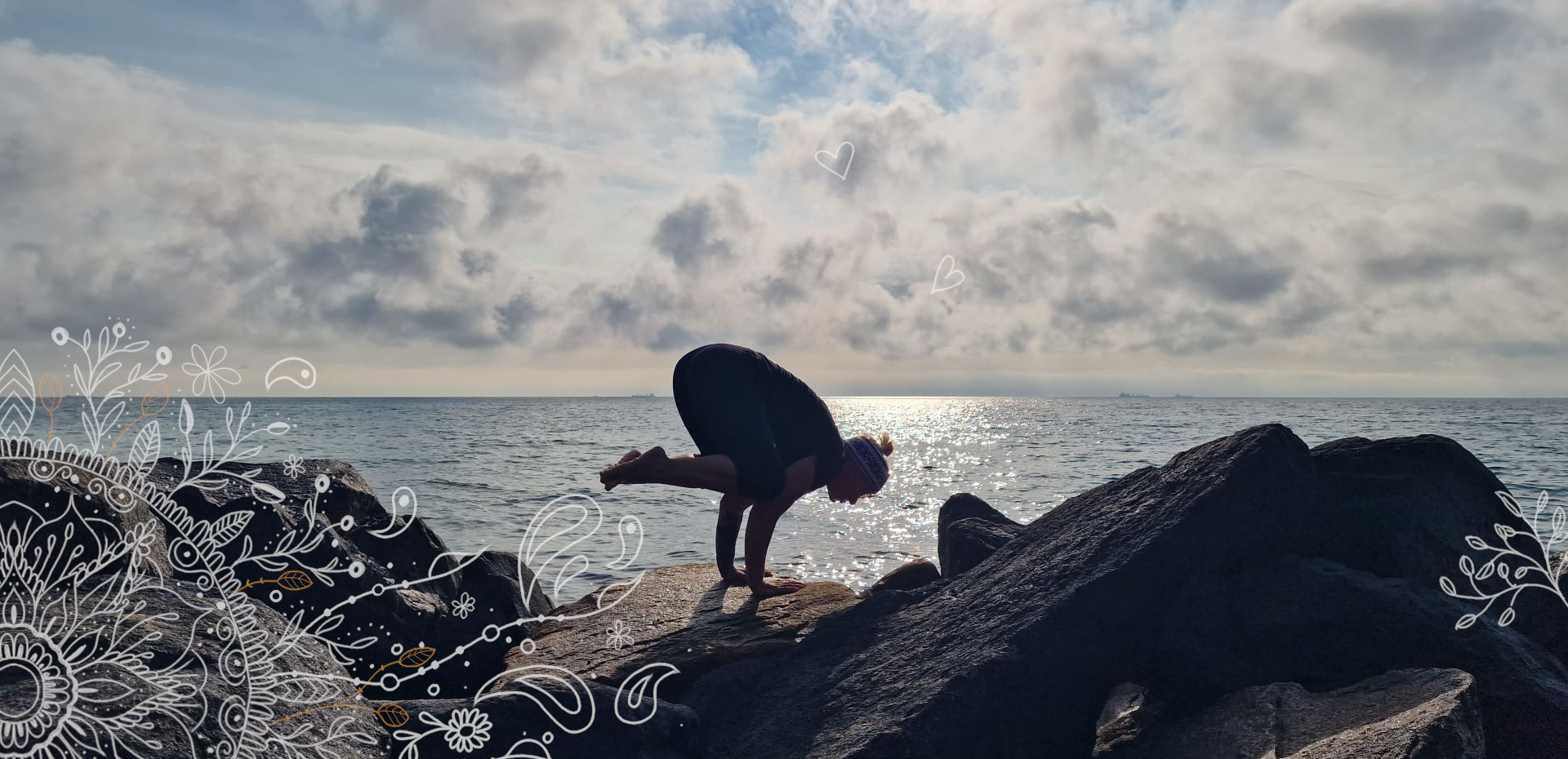 Frau in Yoga-Pose auf Händen auf Felsen. Im Hintergrund das Meer und der Himmel.