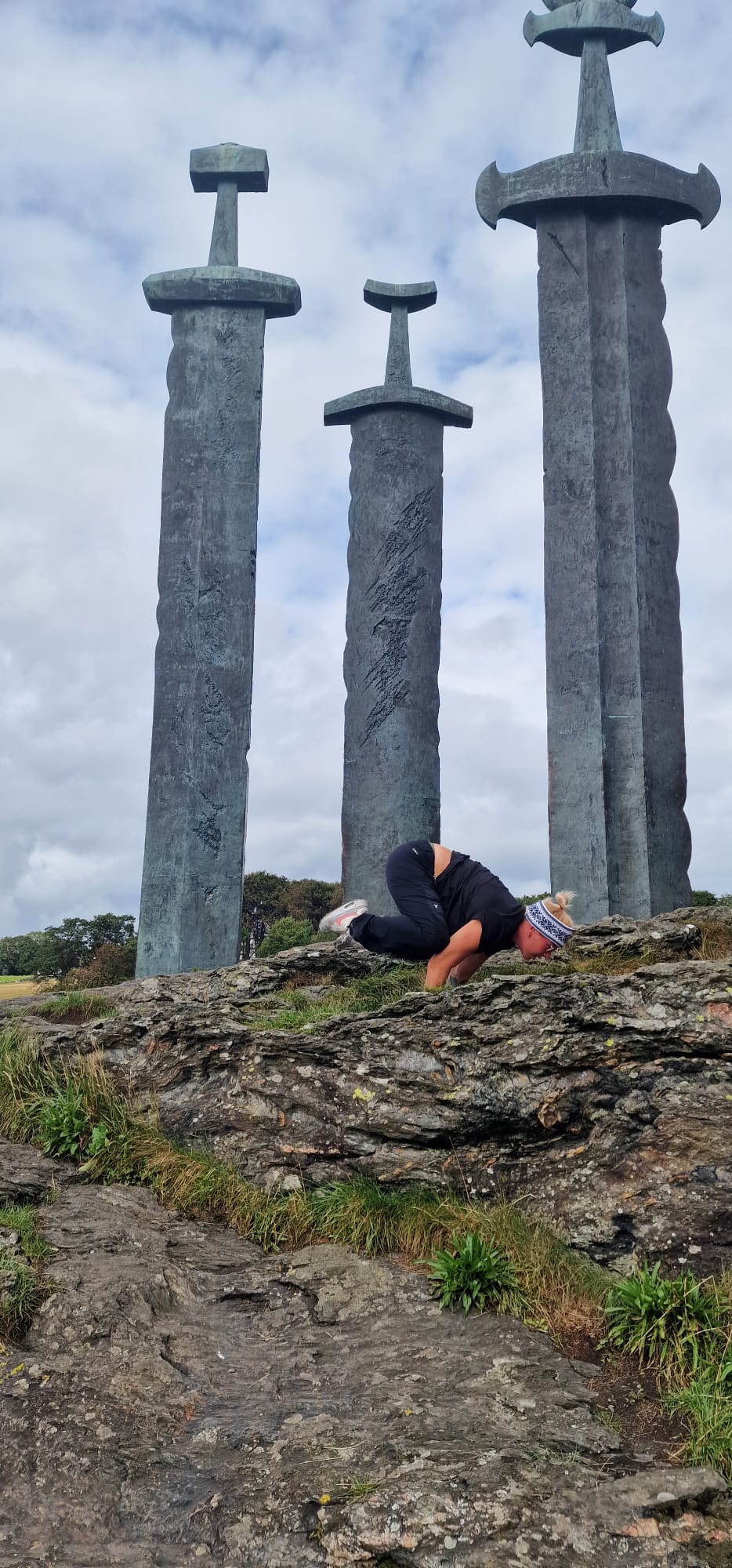 Frau in Yoga-Pose auf Händen auf Felsen. Im Hintergrund drei Türme.